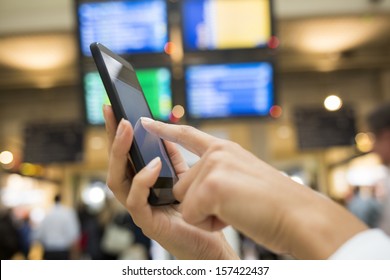 Close up of hands woman using her cell phone in station, background time display panels - Shutterstock ID 157422437