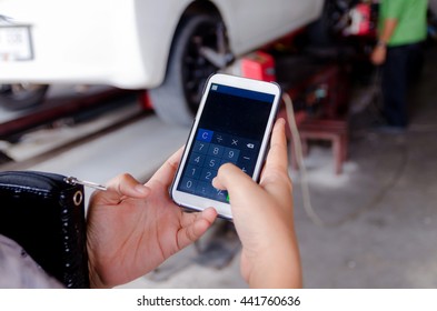 Close up hands of woman using mobile smart phone calculator application in the garage
