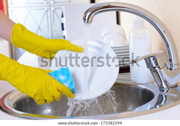 Close up\
hands of woman washing dishes in\
kitchen
