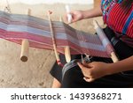 Close up of hands of a woman weaving on an old wooden loom.