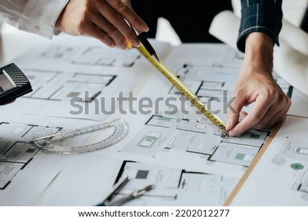 Close up of hands working brainstorming and measuring for cost estimating on paperworks and floor plan drawings about design architectural and engineering for houses and buildings.