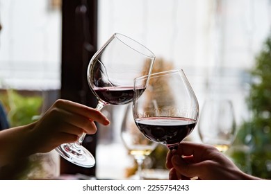 Close up of hands young couple clinking with glasses of red wine at restaurant