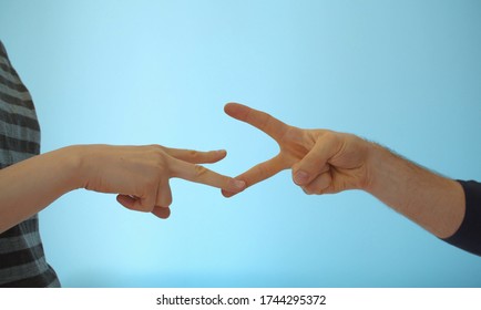 Close Up Hands Of Young Couple Playing Rock Paper Scissors On Blue Background Indoors.