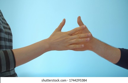 Close Up Hands Of Young Couple Playing Rock Paper Scissors On Blue Background Indoors.