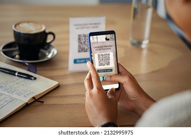 Close up of hands of young woman scanning qr code for cashless payment at cafeteria. Detail of customer hand making payment through smartphone and scan code at cafe. African woman paying with QR code.