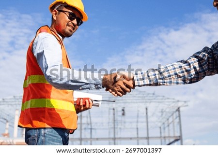Close up handshake of two engineers on produce site. Group of industries workers meet on manufacture site shake hands