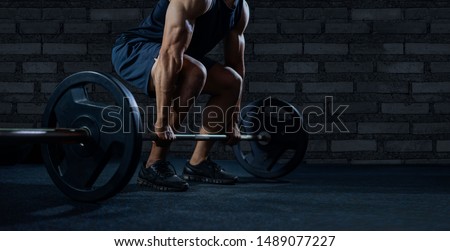 Close up of handsome bodybuilder guy prepare to do exercises with barbell in a gym.bodybuilder's hand is lifting the barbell and exercising in the gym.low key
