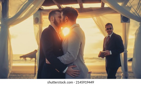 Close Up Of Handsome Gay Couple Exchange Rings And Kiss At Outdoors Wedding Ceremony Venue Near The Sea. Two Happy Men In Love Share Their Vows And Get Married. LGBTQ Relationship Goals.