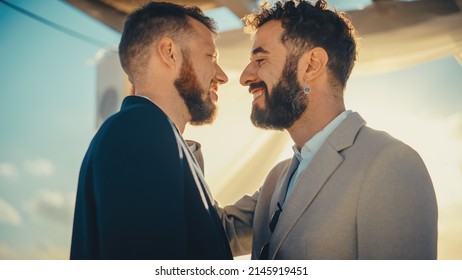 Close Up Of Handsome Gay Couple Exchange Rings And Kiss At Outdoors Wedding Ceremony Venue Near The Sea. Two Happy Men In Love Share Their Vows And Get Married. LGBTQ Relationship Goals.