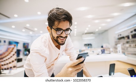 Close up of handsome young man buying new mobile in the electronic shop. - Powered by Shutterstock