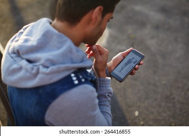 Close Up Handsome Young Man Using Smart Phone While Standing Outdoors At Sunny Evening, Rear View Shot Hipster Man Holding Cell Phone While Looking To Some Fashion Website On Mobile Screen