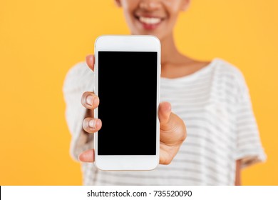 Close up of happy african lady showing smartphone with blank screen and smiling isolated