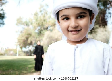 Close up of Happy Arab boy with mother on the back. Young Middle East student on Kandora with his parent looking after him. Loving mom spending time with her child for happiness concept