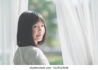 Close Up Of Happy Asian Girl Opening Window Curtains