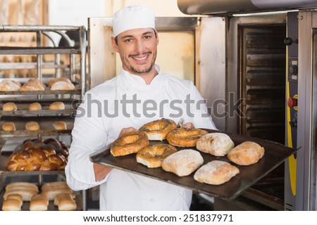 Close up of happy baker showing tray of fresh bread in the kitchen of the bakery
