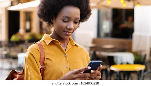 Close up of happy beautiful African American girl texting on mobile phone while standing outdoor.  - Shutterstock ID 1824800228