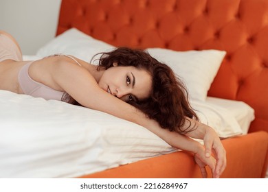 Close Up Of Happy Beautiful Caucasian Cute Woman With Curly Dark Hair In Bra And Panties Lying On Stomach In Bed At Home. Lazy Morning In Bedroom. Pretty Young Female With Slim Body Resting Indoors