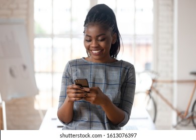 Close up of happy biracial millennial female employee using modern cellular texting messaging via wireless internet connection, smiling african American businesswoman browsing smartphone in office - Powered by Shutterstock