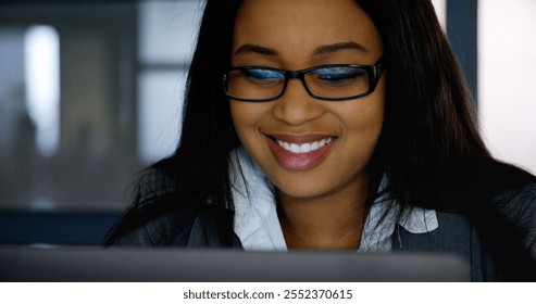 Close up of a happy businesswoman using laptop in office. The biracial woman wearing glasses work on the computer. - Powered by Shutterstock