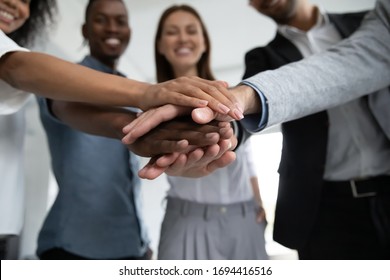 Close up happy diverse business people putting hands together, showing support and unity. Multiracial colleagues involved in team building activity. Staff training concept, start working together. - Shutterstock ID 1694416516