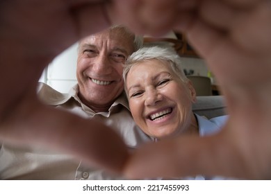 Close Up Happy Faces Of Older Married Couple Look At Camera, Join Their Fingers, Showing Symbol Of Love. Senior Affectionate Spouses Demonstrating Sincere Feelings, Expressing Unity. I Love You Sign