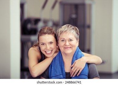 Close Up Happy Fit Daughter Leaning To Healthy Mom While At The Fitness Gym, Looking At The Camera.