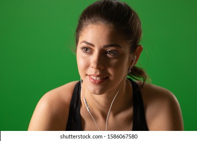 Close up of happy fitness woman listening to music on greenscreen. Portrait of Caucasian athlete wearing earbuds - Powered by Shutterstock