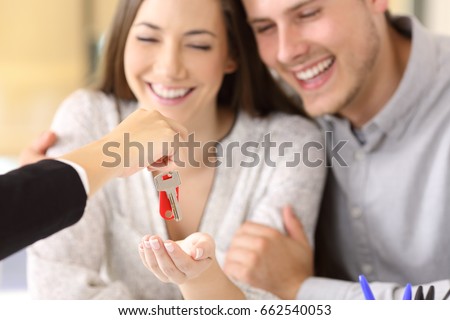 Close up of a happy homeowners receiving their new house keys from a real estate agent at office