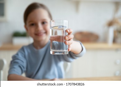 Close up of happy little Caucasian girl offer crystal still mineral water for body refreshment, smiling small European child recommend daily dose of clean aqua, dehydration, healthy lifestyle concept
