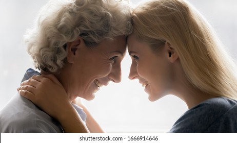 Close up of happy mature mother and grownup girl child look in eyes touch forehead enjoying close intimate moment together, smiling senior mom and adult daughter hug show love and care