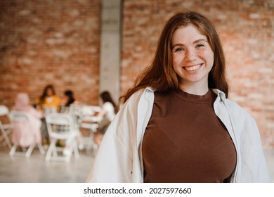 Close Up Of A Happy Mid Aged White Woman Standing Looking At Camera With Group Of Multiethnic Women Sitting At The Table Indoors During Seminar Only For Women, Feminism Concept