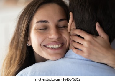 Close Up Of Happy Millennial Girl Hug Beloved Boyfriend Feel Overjoyed Show Love And Affection, Smiling Young Woman Or Wife Embrace And Cuddle Husband Enjoy Tender Romantic Sweet Moment Or Date