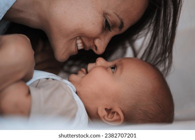 Close up happy scene mom and son are playing and cuddling in bed, touching noses - Powered by Shutterstock