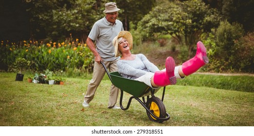 Close up of happy senior couple playing with a wheelbarrow in a sunny day - Powered by Shutterstock