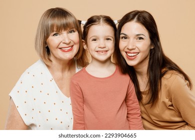 Close up happy smiling cheerful women wear casual clothes with child kid girl 6-7 years old. Granny mother daughter posing looking camera isolated on plain beige background. Family parent day concept - Powered by Shutterstock