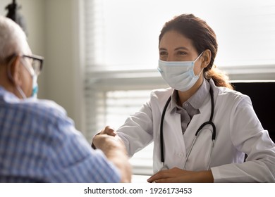 Close Up Happy Smiling Female Doctor Wearing Medical Face Mask And Uniform Shaking Mature Patient Hand, Greeting, Celebrating Good News, Checkup Result, Elderly Man Making Health Insurance Deal