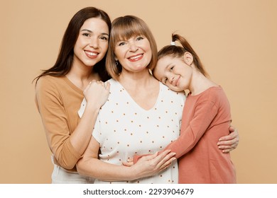 Close up happy smiling women wear casual clothes with child kid girl 6-7 years old. Granny mother daughter posing look camera hug cuddle isolated on plain beige background. Family parent day concept - Powered by Shutterstock