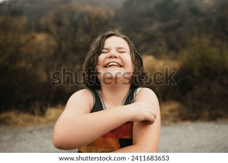 Close up of happy tween girl in pride shirt laughing outside in rain