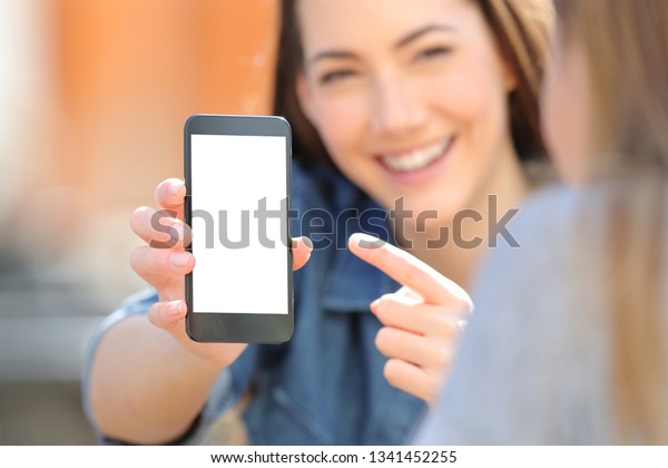 街中の友人に空のスマートフォン画面を示す幸せな女性の手の接写 の写真素材 今すぐ編集