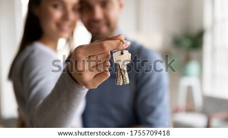 Close up happy woman hugging man, holding keys from new first house, young family celebrating moving day, satisfied customers couple purchase real estate, mortgage and relocation concept