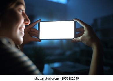 Close Up Of A Happy Woman In The Night Watching Horizontal Blank Smart Phone Screen At Home