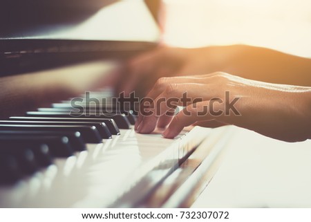 Close up of happy woman's hand playing the piano in the morning.
