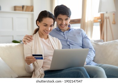 Close Up Happy Young Couple Paying By Plastic Credit Card Online Together, Hugging And Sitting On Couch At Home, Smiling Woman And Man Using Banking Service, Making Secure Internet Payment