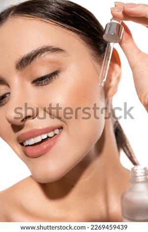 close up of happy young woman holding dropper with vitamin c serum isolated on white