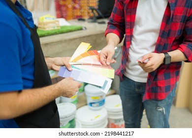 Close Up Of A Hardware Store Employee Showing The Color Swatches To A Young Man Shopping For Paint 