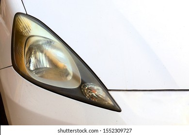 Close Up Hazy Yellowed Dirty Car Headlight. Unpolished Cloudy Foggy Front Headlight Of Old Car. Car Headligh Cleaning Concept.