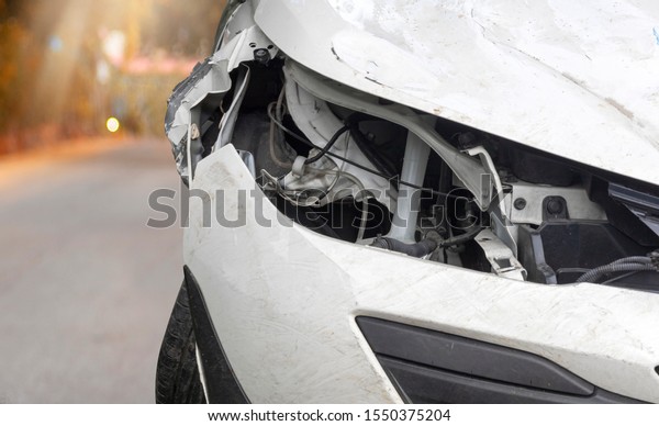 Close\
up head light of  white color car have damaged and broken by\
accident on road parking can not dirve any more.\
