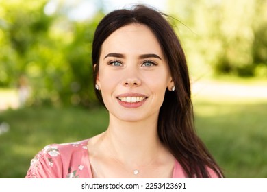 Close up head portrait of smiling caucasian woman with white teeth looking at the camera. Perfect healthy smile with veneer. Skin and dental care. Nature green background.

 - Shutterstock ID 2253423691