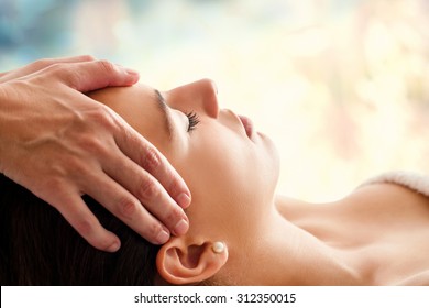 Close up head portrait of young woman having facial massage in spa. Therapist doing head massage  against colorful background. - Powered by Shutterstock