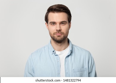 Close up head shot confident serious concentrated young man looking at camera studio portrait, isolated on grey white studio background. Thoughtful millennial guy posing for album photo. - Shutterstock ID 1481322794